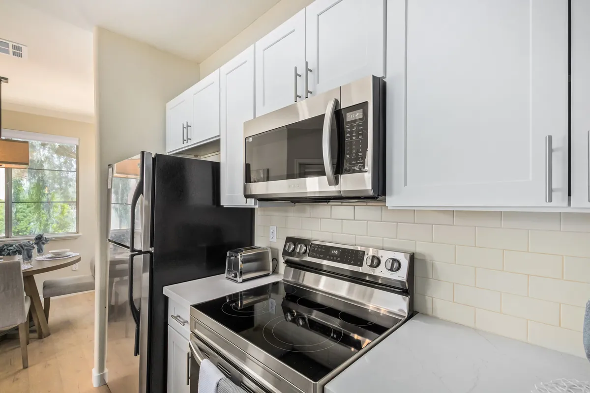 A modern kitchen with stainless steel appliances, white cabinetry, and a clean granite countertop. The space is sleek, functional, and perfect for cooking or hosting gatherings.