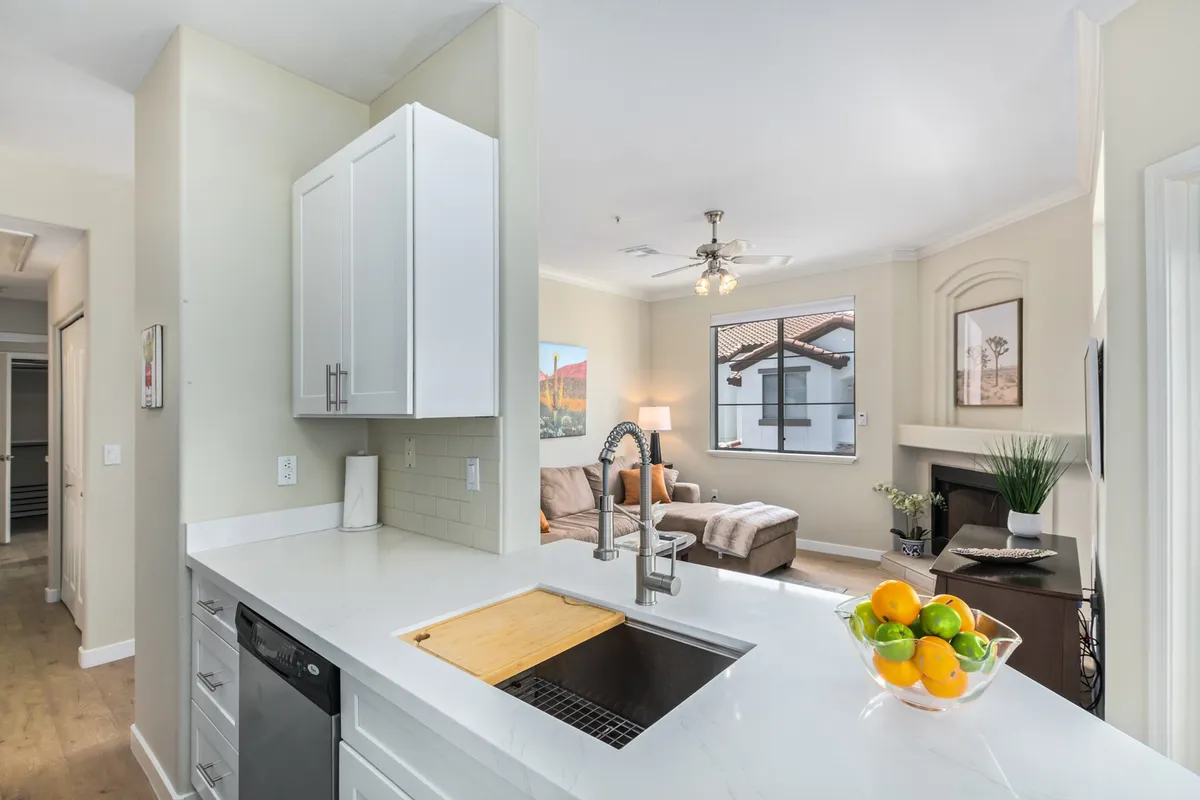 This image shows a bright, sunlit kitchen that opens into a cozy living area. Natural light streams through a large window, illuminating the inviting space—ideal for relaxing or hosting intimate gatherings after a day exploring the city.