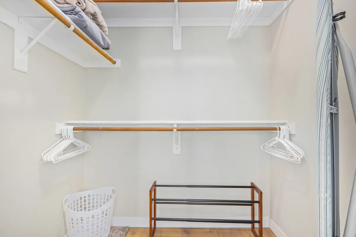 A calm, organized space dedicated to laundry and storage, featuring a clothes rack, storage basket, and shelves. The image conveys convenience and order, essential for guests planning an extended stay.