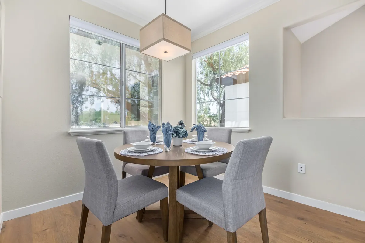A welcoming dining area with a round wooden table, decorative blue accents, and a charming light fixture above. The space exudes warmth and is ideal for shared meals or morning coffee.
